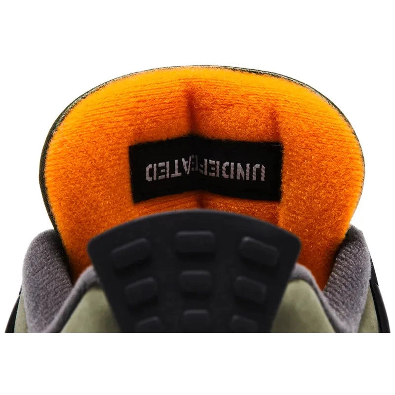 Undefeated x Air Jordan 4 (2025 reissue) in olive nubuck with black wings/eyelets, Nike Air heel tab, orange lining, Velcro tongue patches, off-white midsole, visible heel Air unit.